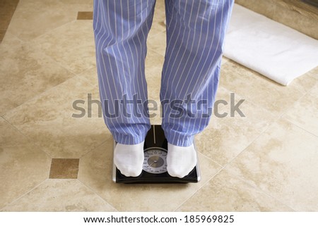 Mature man on bathroom scale (low section)