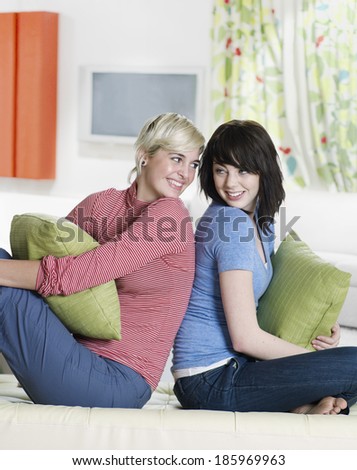 Two Young Women Sitting Back to Back