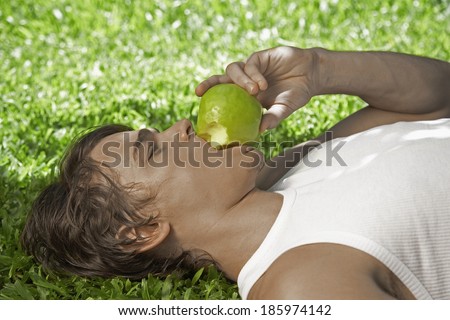 Young Man Eating Apple on Lawn