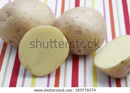 Three raw potatoes, one cut in half.