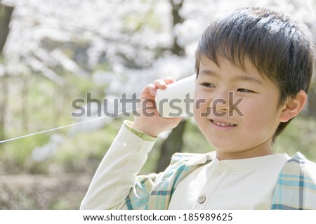 boy putting string telephone on his ear
