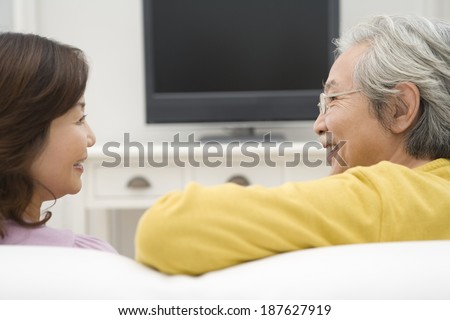 senior husband and wife talking in front of TV