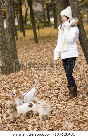 woman talking on mobile phone while taking a walk with dog