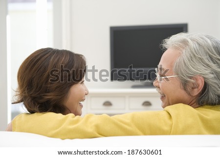 senior husband and wife talking in front of TV