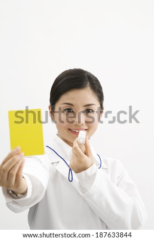 A female doctor holds up a yellow card and prepares to blow the whistle.