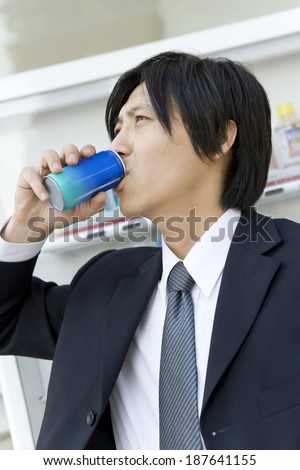 man drinking canned coffee in front of vending machine