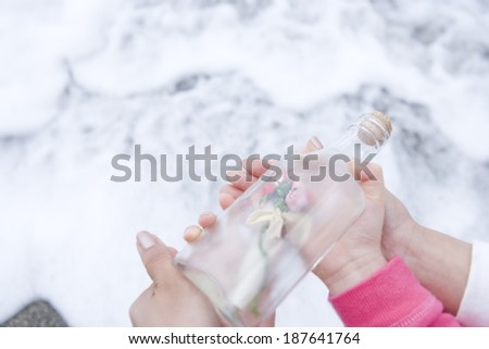 hand of parents and child throwing bottle containing message into sea