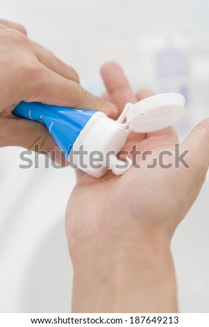 hand of man squeezing cleansing foam out of a tube