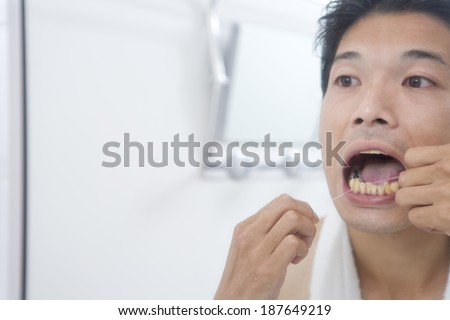 man flossing teeth with dental floss