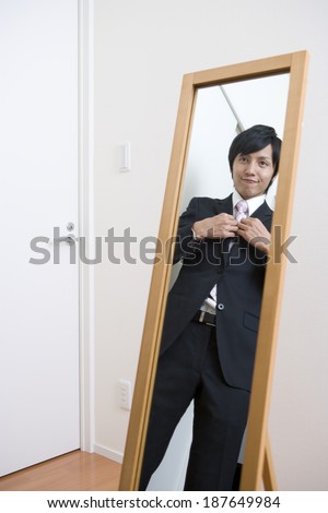 businessman looking at mirror adjusts jacket