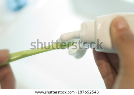 hand squeezing toothpaste out of a tube