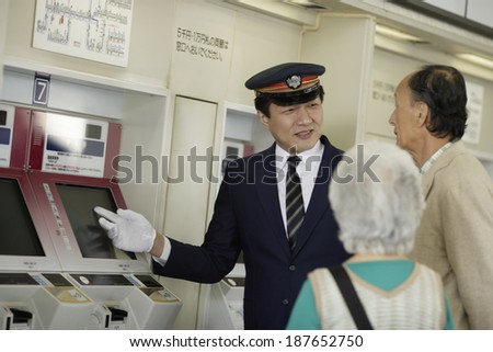 senior husband and wife having conversation with station staff at ticket machine