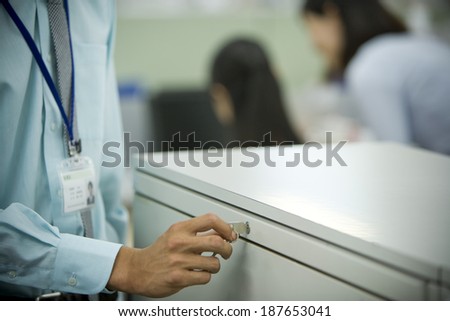 male office worker trying to open cabinet with key