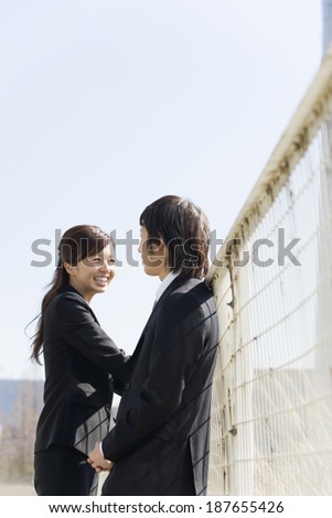 man and woman talking in front of fence