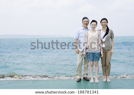 smiling family standing in front of blue sea