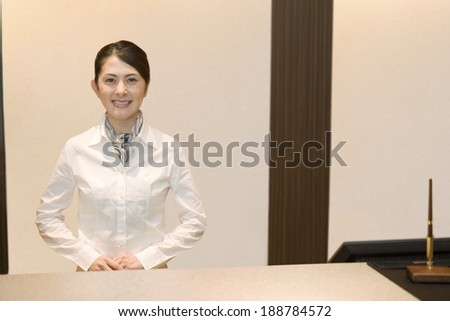 smiling female office worker standing still in front desk