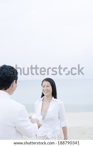 husband trying to give wife gift on beach