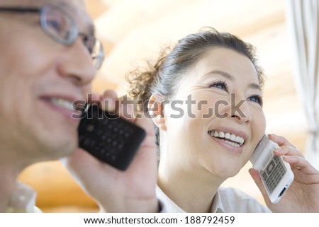 senior husband and wife talking on mobile phone