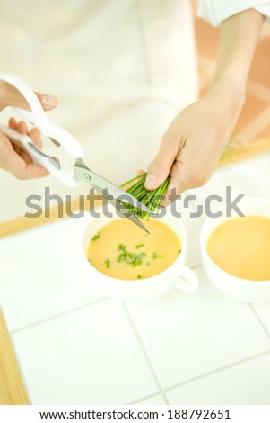Hand of woman picking chive for garnish of soup