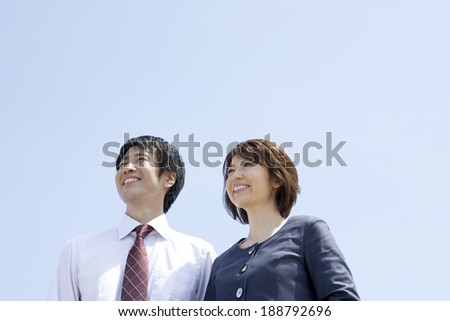 man and woman smiling with their back against blue sea