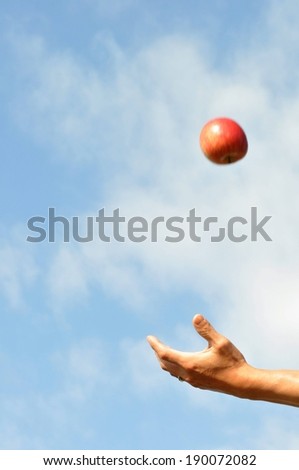 A hand throwing a red apple into the air.