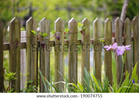 A little wood fence with flowers near by.