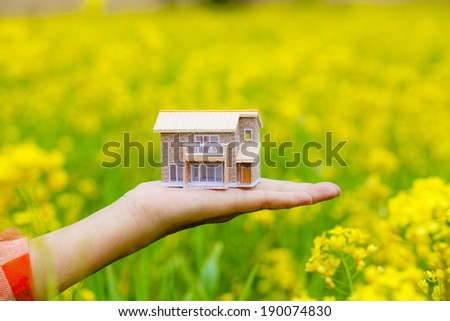 An open hand turned upwards and holding a small house structure.