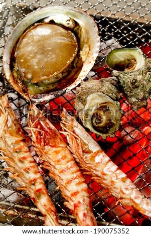 Various pieces of seafood covered in sauce on a grill.