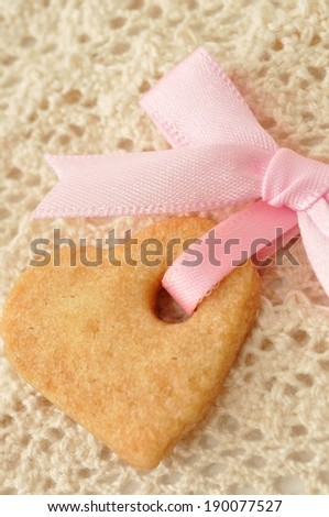 A cookie with a pink ribbon attached on a knitted cloth.