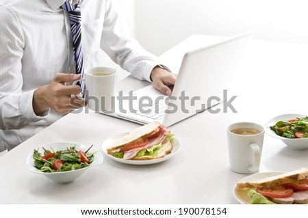 A businessman eating lunch while on the computer.