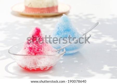 Two bowls of shaved ice with spoons in them.