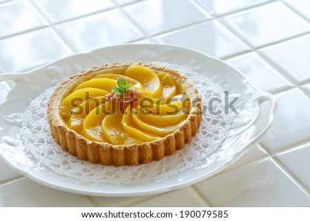 A peach tart on a white serving dish
