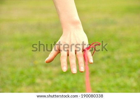 A hand with a red ribbon tied around a finger.