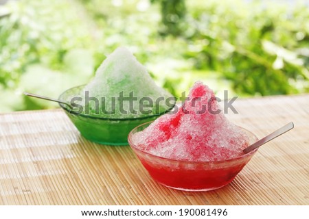 Two bowls of colored shaved ice with spoons.