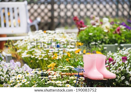 A pair of small pink rain boots in a garden.