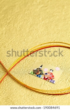 Gold and red rope encircle a card with felt people on it.