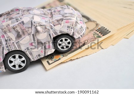 A small car made out of paper money placed on top of thousand dollar notes.
