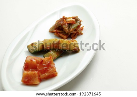 A variety of foods in a red sauce sit on a white platter.