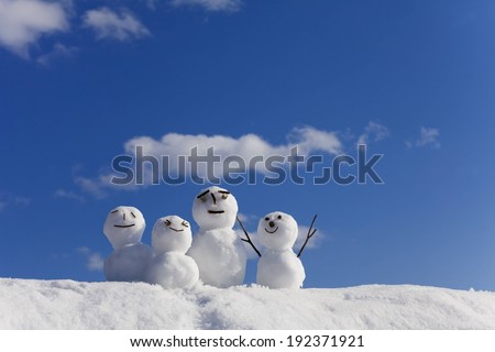 Four mini snowmen on top of a snow bank.