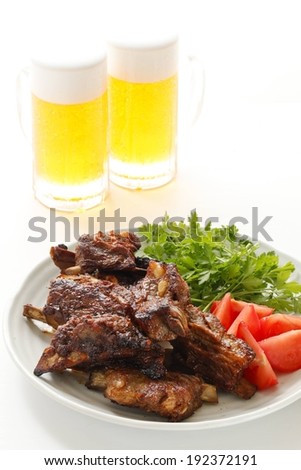 Two glasses beside a plate of meat, tomatoes and lettuce.
