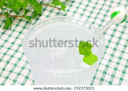 A clear cup of water on a tablecloth.