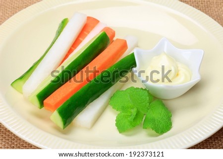 A white plate with chopped carrots, cucumber and some dip on the side.
