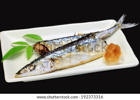 A white dish holding two cooked fish and a leaf.