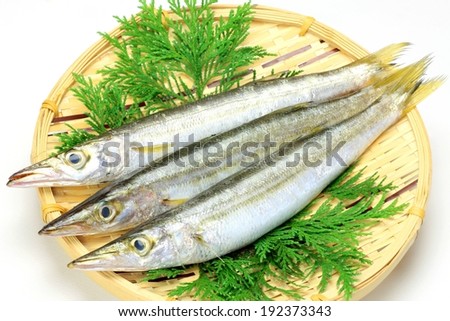 Three long silver fish displayed on some greens in a wicker basket.