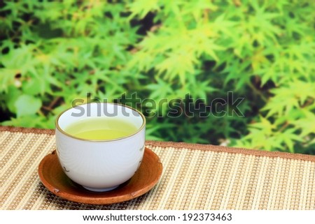A cup of tea sitting on a mat outside.