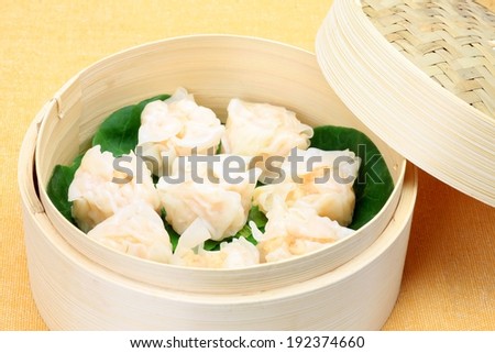 A wooden, wicker basket of dumplings and leaves.