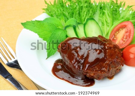 Gravy covered beef, salad and tomatoes served on a plate.