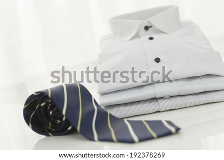 A striped tie in front of folded shirts.