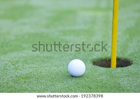 A hole on a golf course with a golf ball approaching it.