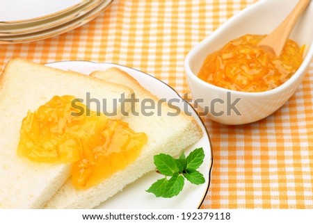Mango jelly spread on two bread slices and a garnish.